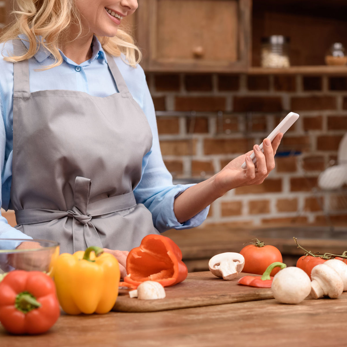 mujer en la cocina con móbil iStock